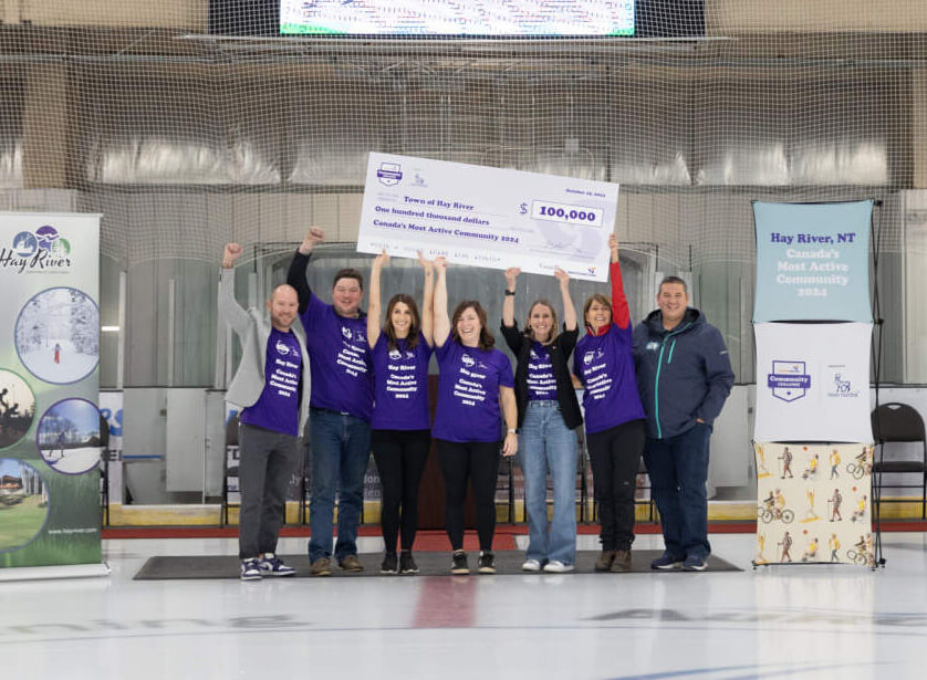 Hay River residents holding up a large $100,000 cheque on an ice rink