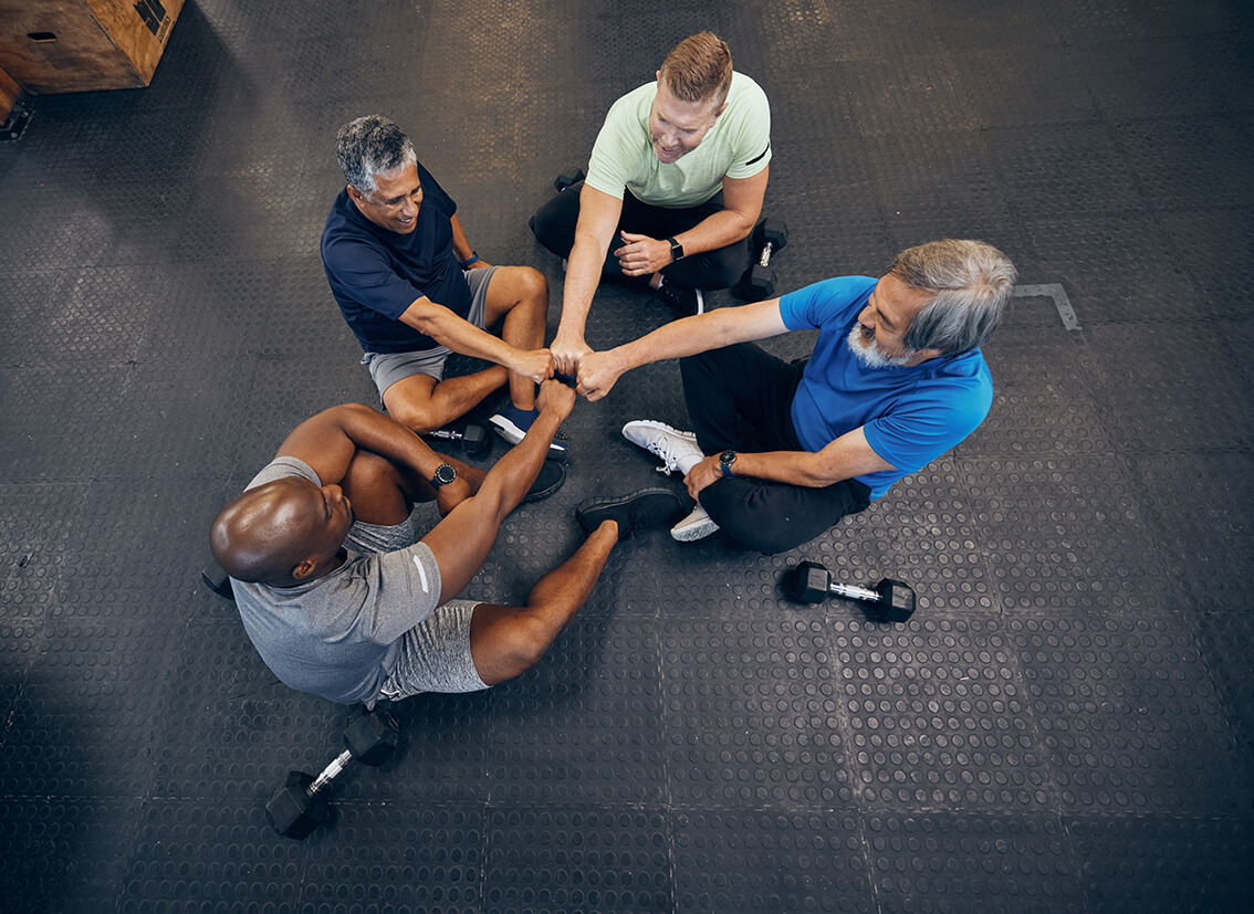 A group of people fist-bumping while sitting on a gym floor