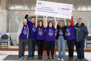 Residents of Hay River, Northwest Territories holding up an over-sized cheque on an indoor ice rink.