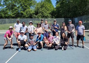 A group of people posing for a photo on a tennis court.
