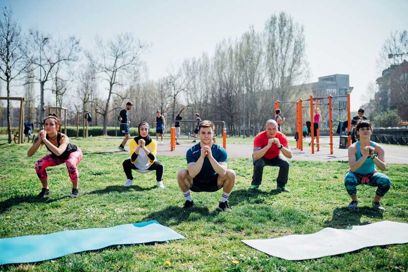 Un groupe de personnes fait des flexions des jambes dans un parc. 