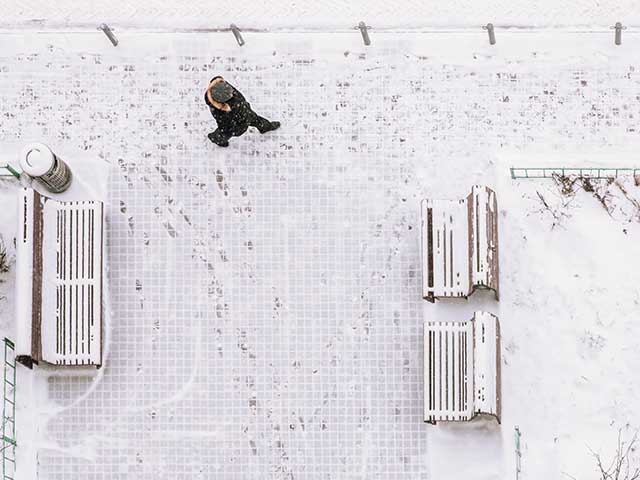 An aerial view of a person walking in a snow-covered park