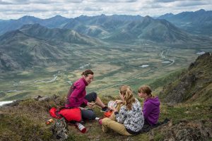 A mother and her two daughters picnicking on a mountain top.