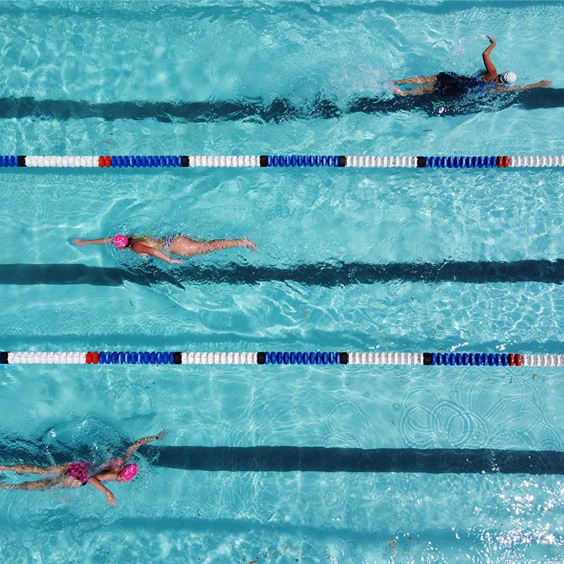 Un groupe de personnes fait des longueurs dans une piscine.  