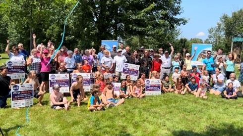 Salisbury residents cheering and holding up Community Challenge signs in a park.