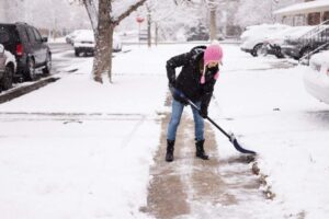 A woman shoveling snow, a great way to exercise in the winter.