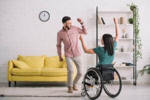 A man dancing beside a woman dancing in a wheelchair. They dance like no one's watching.