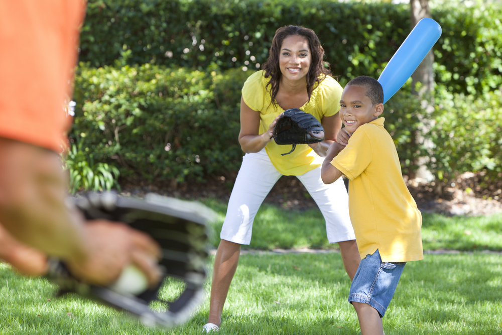 A mom and her son playing baseball at a park. A mom and her son playing baseball at a park.