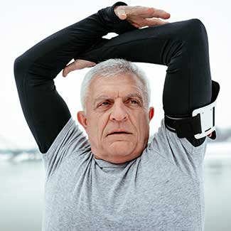 older man holding his other elbow over his head for a stretch