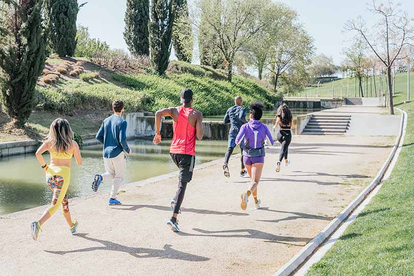 A group of young adults running together at a park. A group of young adults running together at a park.
