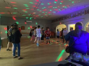 A group of people dancing in a large room while wearing headphones. A group of people dancing in a large room while wearing headphones.