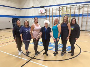 A group of women holding batons on a basketball court.