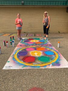 Move Your Mood coordinator Denise Fredeen standing beside her daughter on spray-painted tarmac. 