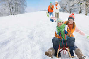 Family having fun with a toboggan on the snow