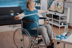 An older woman in a wheelchair using a resistance band. 