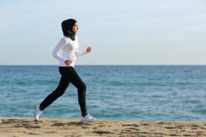 A Muslim woman jogging on a beach during Ramadan. 