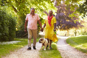 A couple walking their dog on a nature trail. 