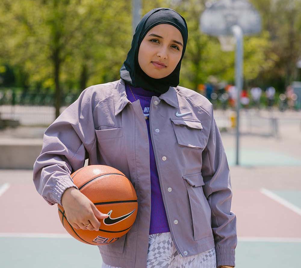 Amreen Kadwa tient sur un terrain de basket tout en tenant un ballon de basket. Amreen Kadwa tient sur un terrain de basket tout en tenant un ballon de basket.