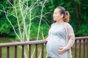 Une femme enceinte marche sur un pont en pleine conscience des arbres qui l’entourent.