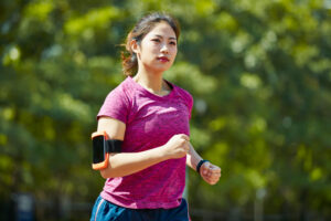 A woman jogging with a phone attached to her arm to help her with tracking steps. 