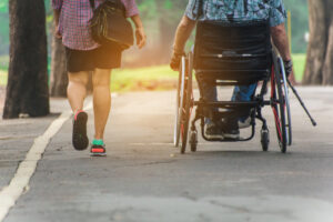 A person walking beside a person wheeling on a sidewalk. 