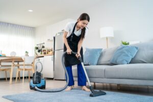 A woman vacuuming a rug to get more steps. 