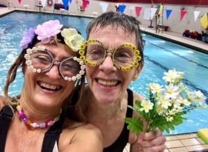 two smiling senior women with swimming pool background