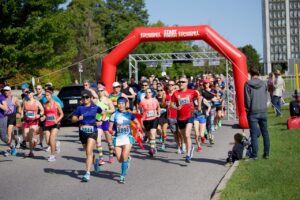 Les participants et participantes de la Course de la Fierté dans la Capitale Nationale courent sur une route