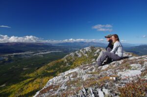 2 personnes assises sur une falaise surplombant les montagnes