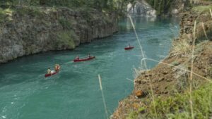 Trois canoës rouges descendant une rivière au Yukon