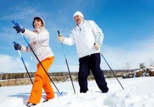 Two smiling people snowshoeing on a nature trail.