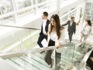 Four people in business attire walk up a set of stairs as part of their habit stacking routine.