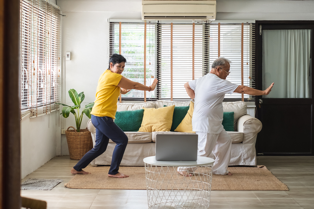 A man and woman doing tai chi in a living room. A man and woman doing tai chi in a living room.