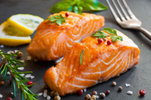 Two filets of salmon and two lemon slices on a plate. 