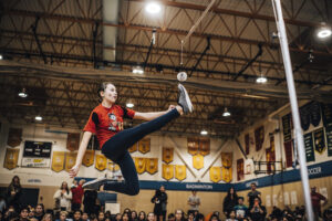 Une fille joue au jeu inuit du coup de pied simple dans un gymnase. 