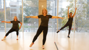 A screenshot of the Better Balance Workout (one of the YMCA exercise videos) that shows three people balancing on one foot in a yoga studio.