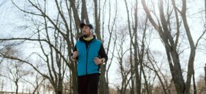 A man jogging on a road with trees behind him.