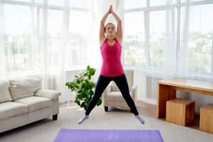 Une femme fait des « jumping jacks » dans son salon.