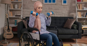 A woman in a wheelchair lifting dumbbells in a living room. Hormones