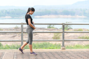 Une femme enceinte marche sur un chemin avec vue sur une étendue d’eau et des montagnes. hormones