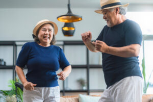 Two people dance in a living room. 