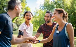 A group of smiling people shaking hands in a community park.