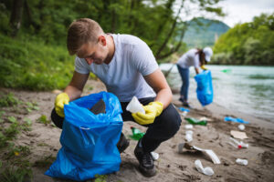 Two people picking up trash on a beach. 