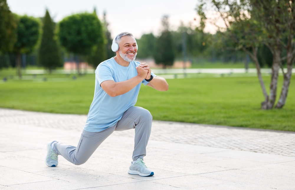 An middle aged man doing lunges on a parks path An middle aged man doing lunges on a parks path