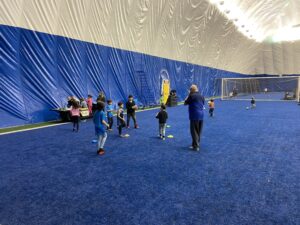 Un groupe d'enfants jouant au rugby dans une salle de sport