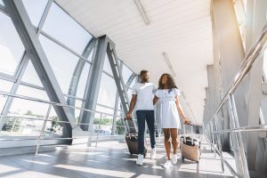 A couple pulling suitcases through an airport.