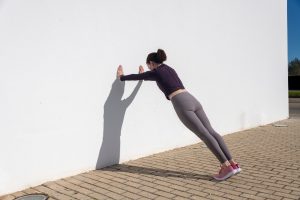 A woman doing a wall push-up.