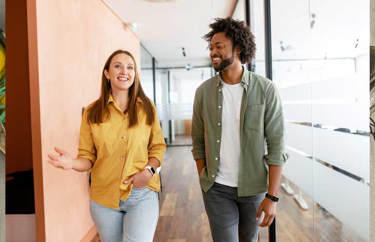 Woman and man smiling walking through office hallway