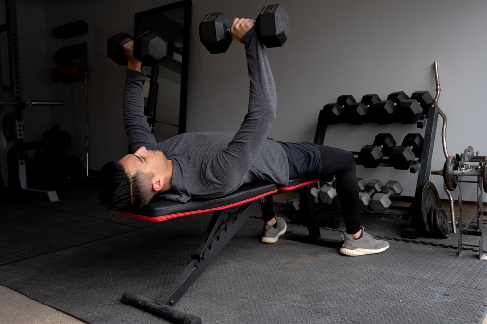 A man doing dumbbell bench presses. 