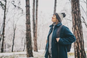 A grinning woman walking in a forest during winter. 